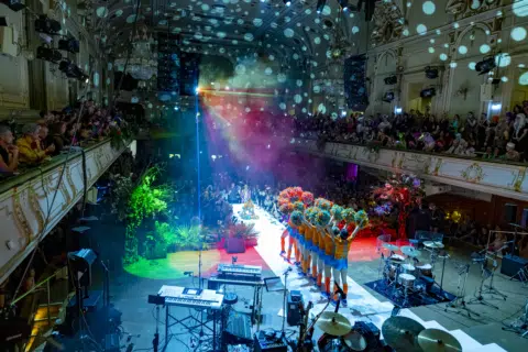 Farbenfrohe Performance mit Tänzern auf der Bühne unter bunten Lichtern