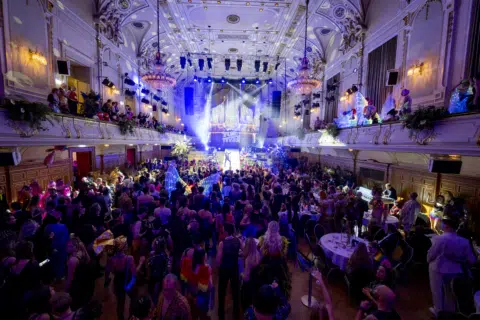 Lebhafte Partyszene in einem festlichen Ballsaal während einer Gala.
