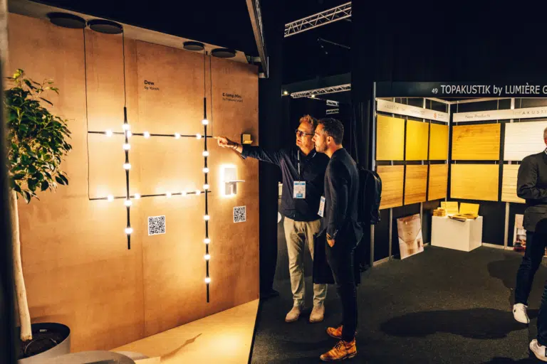Two men discussing lighting design at an exhibition with illuminated wall installations.